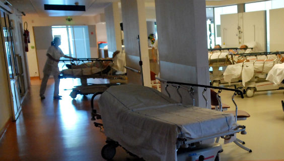 En hospitalsansat kører en seng ind på en hospitalsstue
